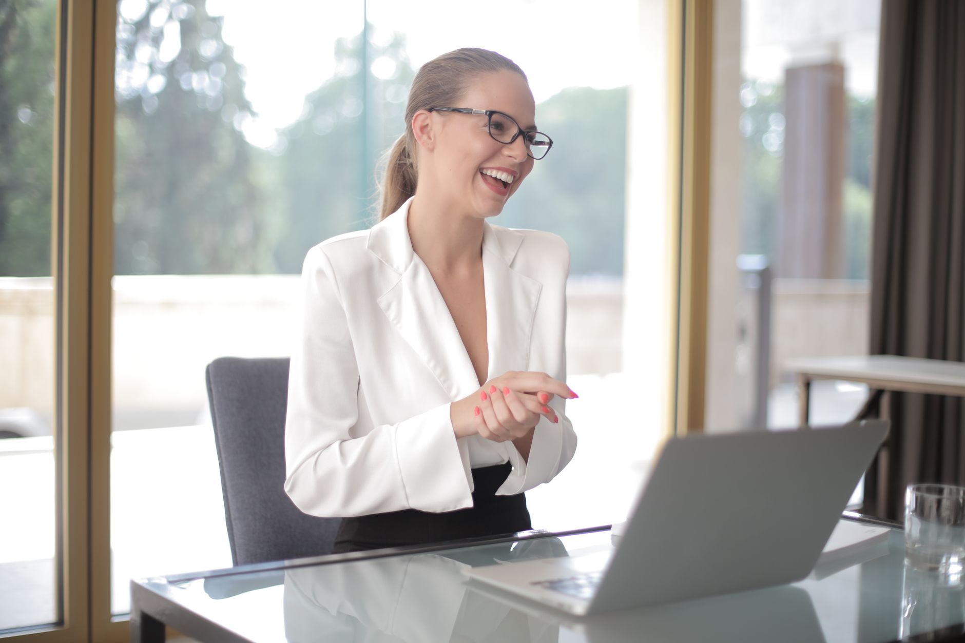 Femme entrepreneure en tenue formelle installée devant un ordinateur portable et des documents dans un bureau moderne